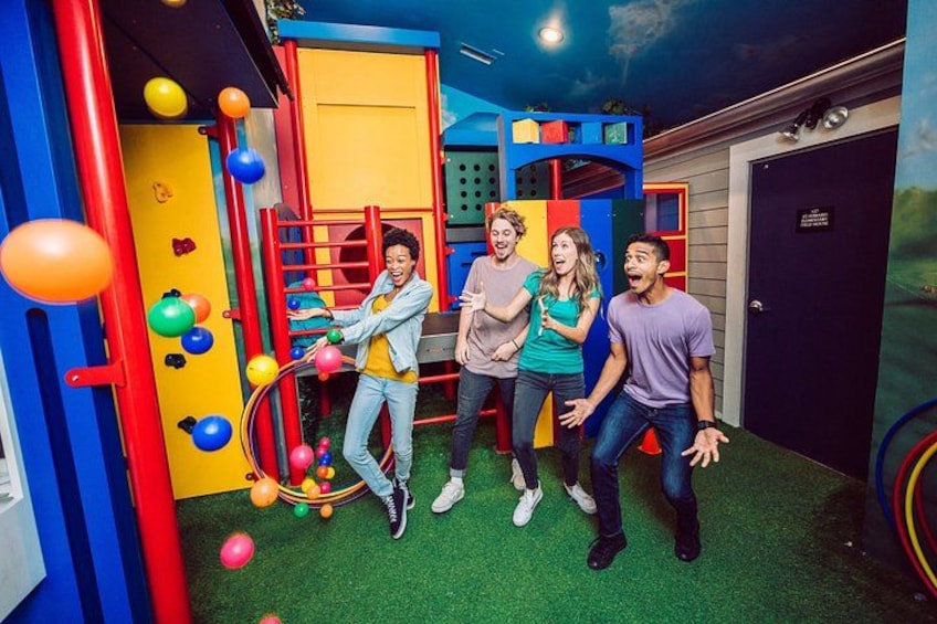 A colorful indoor play area with a climbing wall, a slide, and various play structures. 2