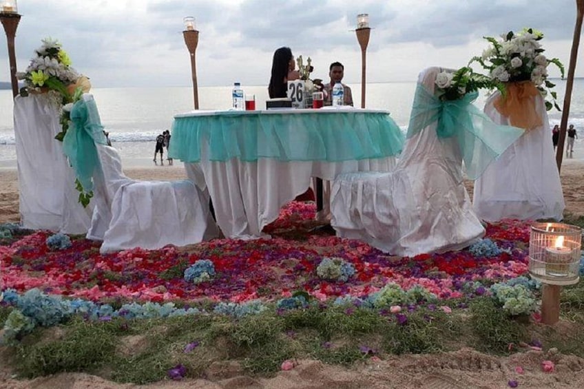 A beach wedding setup with a table, chairs, and floral decorations. 1