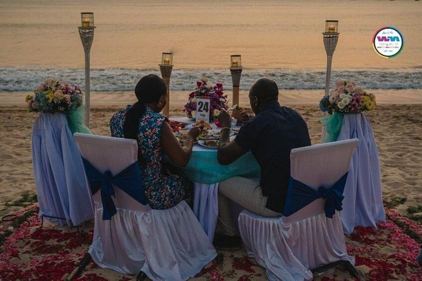 A beachside dining setup with a table, chairs, and a number 24 sign. 3
