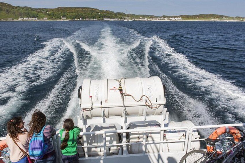 A boat speeding across a body of water with wake patterns, passengers, and a coastline in the background. 3