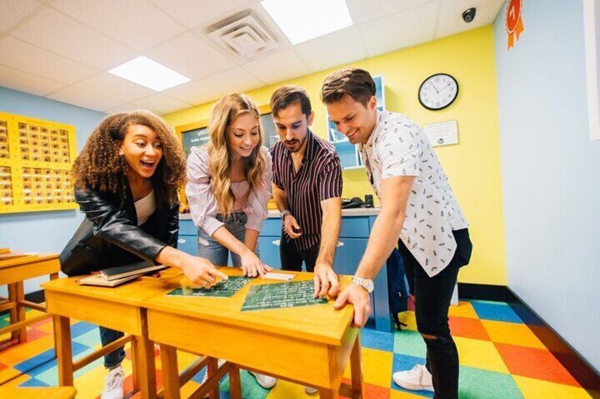Four people working together at a table with a puzzle in a brightly colored classroom. 5