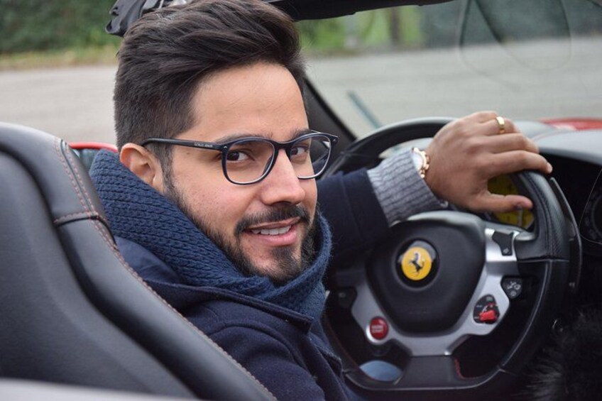 Una persona conduce un auto descapotable con un logo Ferrari visible en el volante. 1