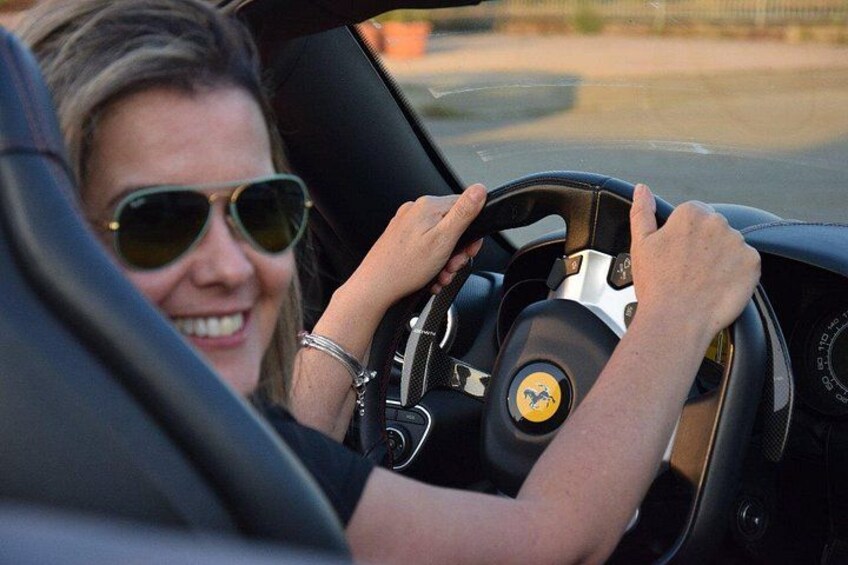 Una persona conduciendo un automóvil con un volante que tiene un logotipo. 2