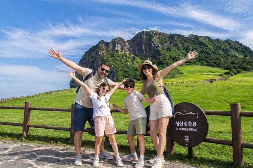 A family posing in front of a sign that reads 'Sunrise Peak.' 1