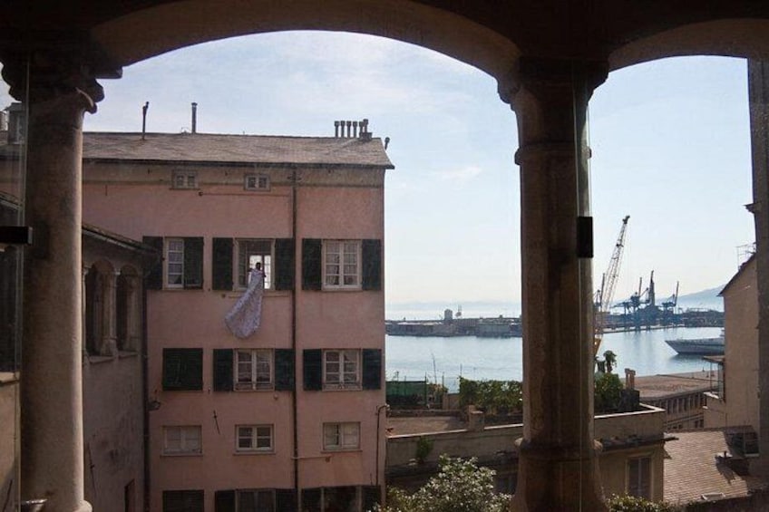 A pink building with a balcony, a view of the sea, and a crane in the distance. 2