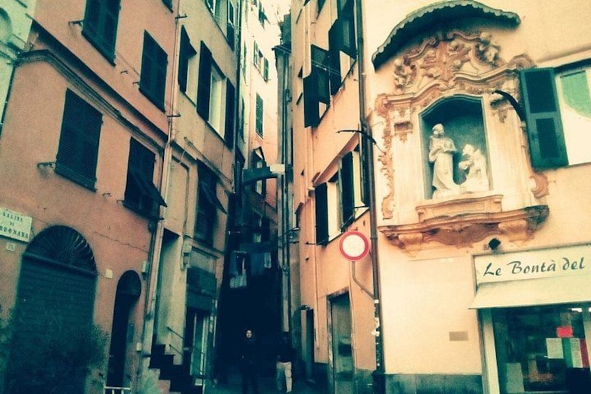 A narrow street with buildings, a red traffic sign, and a shop with a sign reading 'Le Bontà del'. 3
