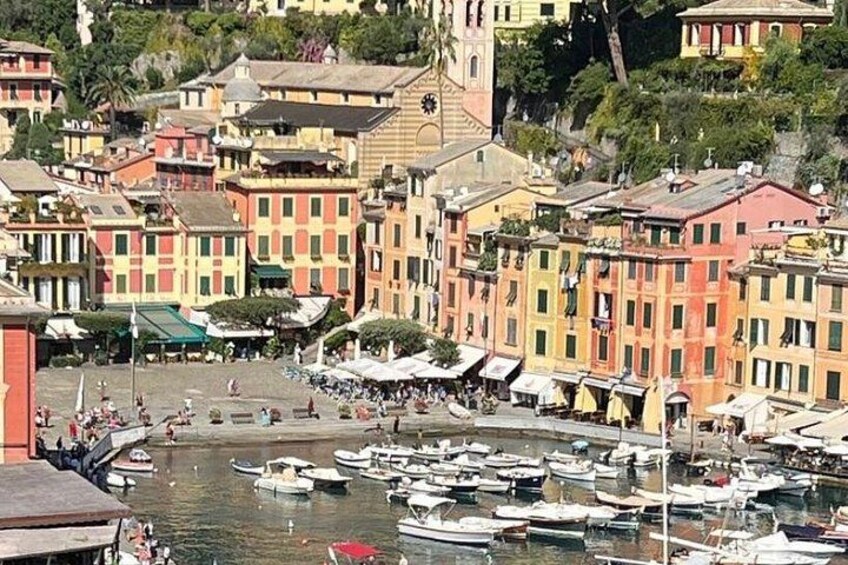A coastal town with colorful buildings, a marina with boats, and a clock tower. 2