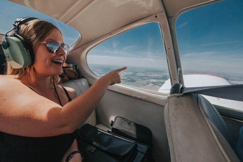 A person in a small aircraft cockpit pointing outside. 1