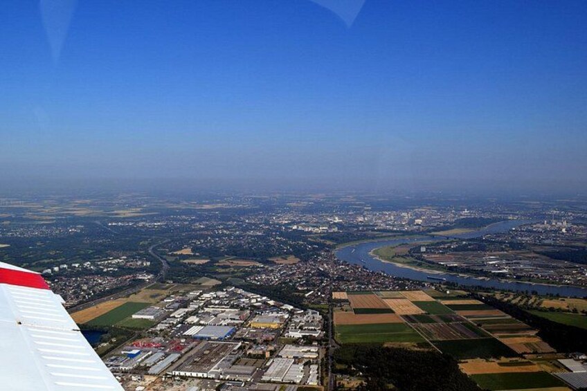 Eine Luftaufnahme einer Stadt mit einem Fluss, einem Industriegebiet und landwirtschaftlichen Feldern. 1