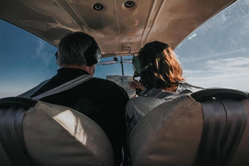 Two people in a cockpit, wearing headsets, with a clear sky outside. 5