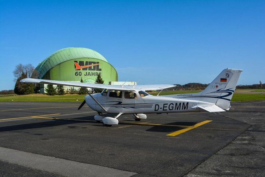 A small white airplane with registration D-EGMM parked on a tarmac. 4