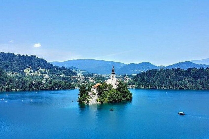 Un lago con una pequeña isla que tiene una iglesia, rodeado de montañas y bosques densos. 1
