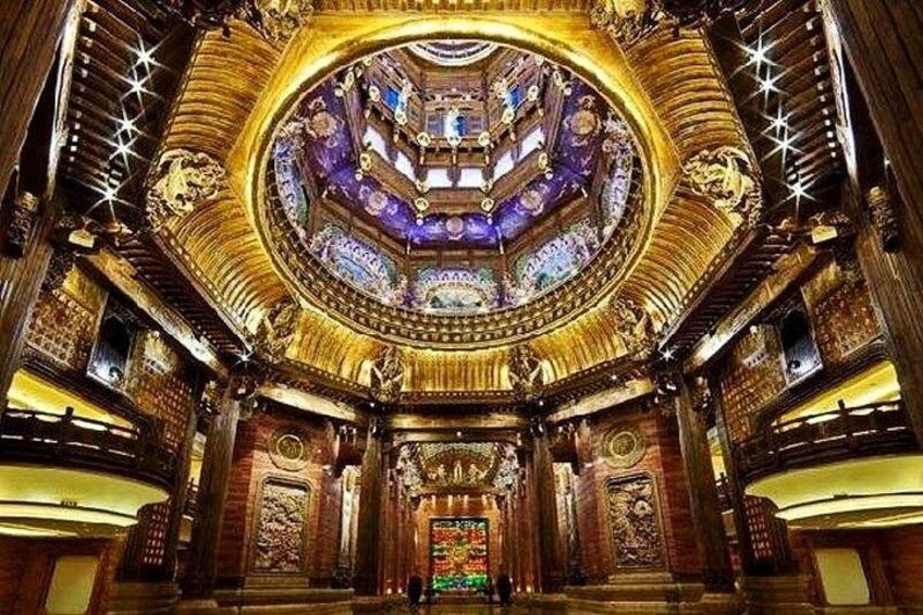 A grand, ornate theater interior with a central circular stage, intricate carvings, and a starry ceiling design. 4