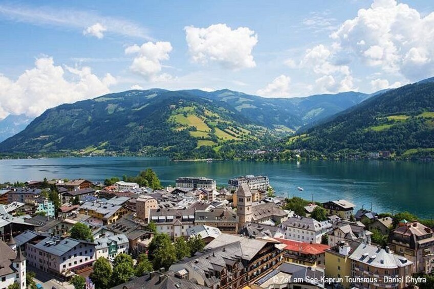 A town by a lake with mountains in the background. 2