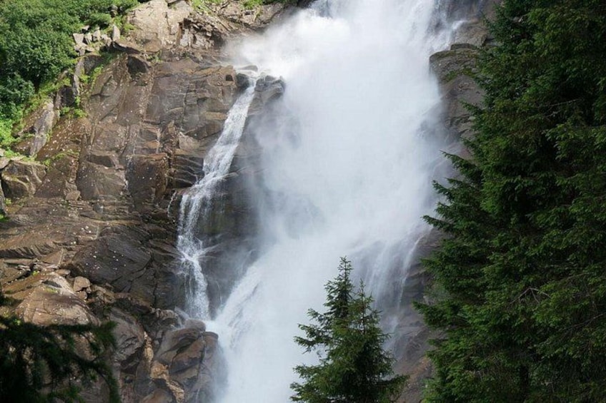 A waterfall cascading down a rocky cliff surrounded by dense green forest. 1