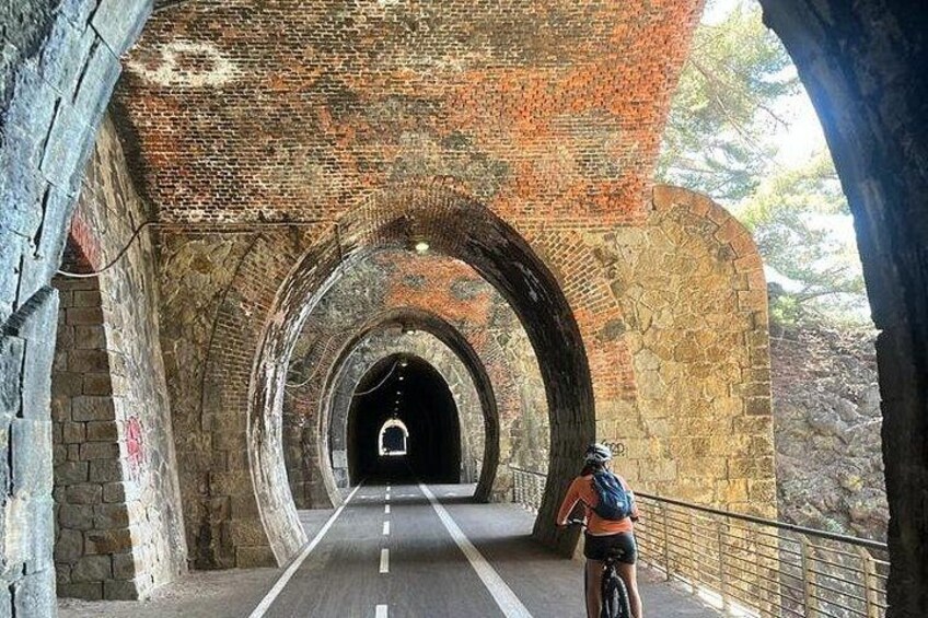 Un cycliste traverse un tunnel en pierre dont les plafonds sont en forme d’arc. 4
