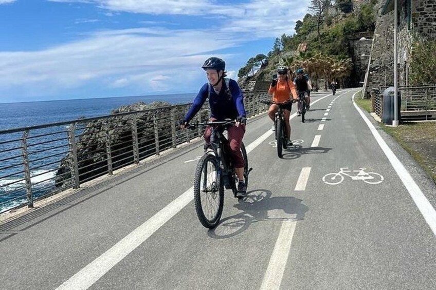 Une piste cyclable asphaltée longe une côte rocheuse, sous un ciel dégagé. 5