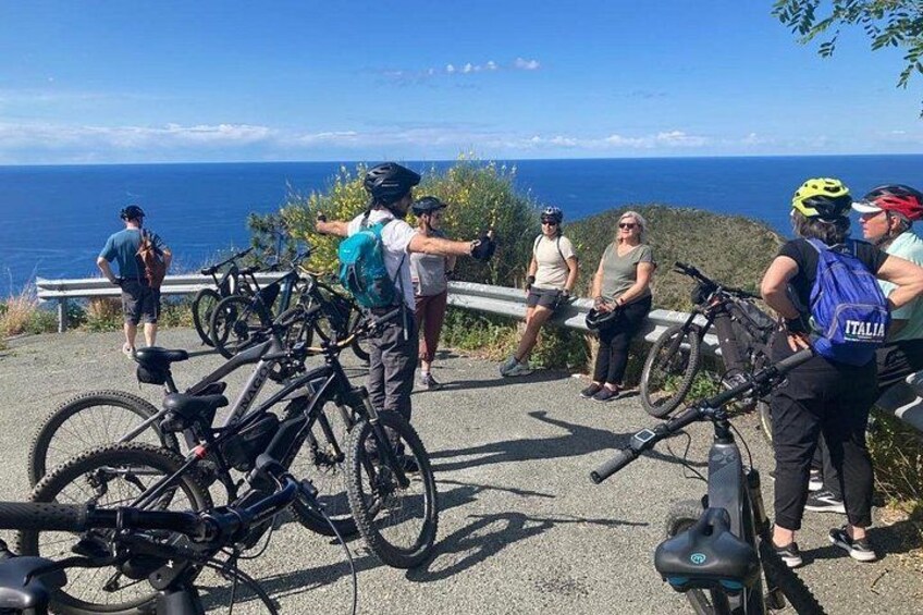 Un groupe de cyclistes se trouve sur un point de vue surplombant la côte, leurs vélos étant garés à proximité, et ils profitent d’une vue panoramique sur l’océan. 2