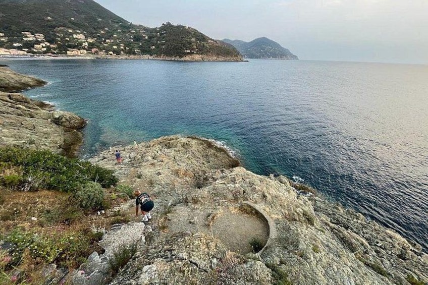 Une côte rocheuse bordée d’une mer d’un bleu limpide, une personne qui fait de la randonnée et des collines qui se dessinent à l’horizon. 3