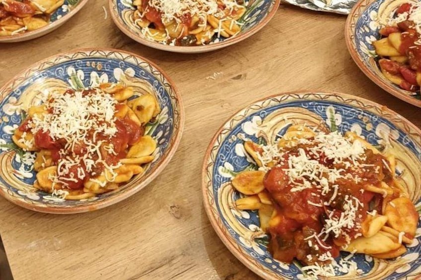Cuatro platos de pasta con salsa de tomate y queso rallado. 1
