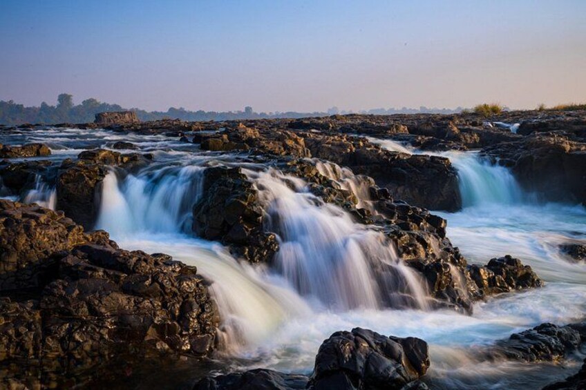 A waterfall cascading over dark rocks, surrounded by a rocky landscape. 5