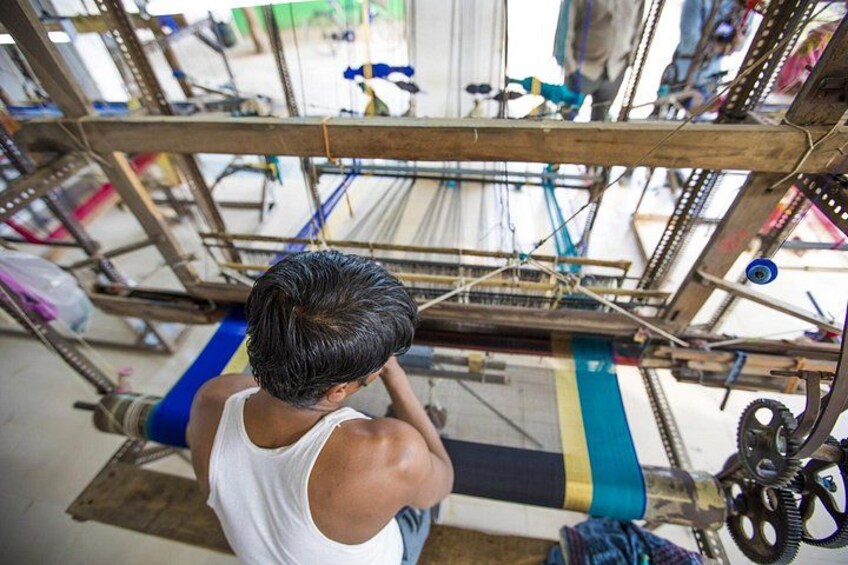 A person working on a loom with a blue and yellow fabric. 2