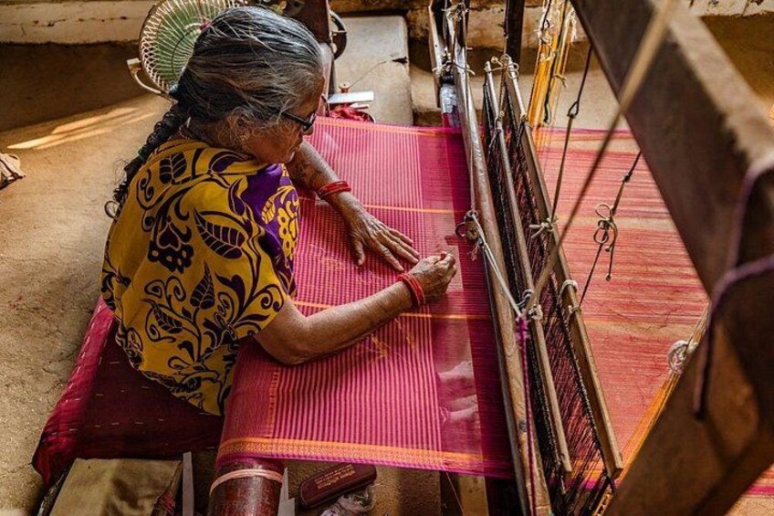 A person weaving on a loom with a red fabric. 3
