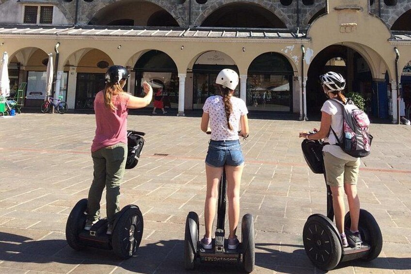 Tres personas en Segways en una plaza con arcos y un edificio al fondo. 4