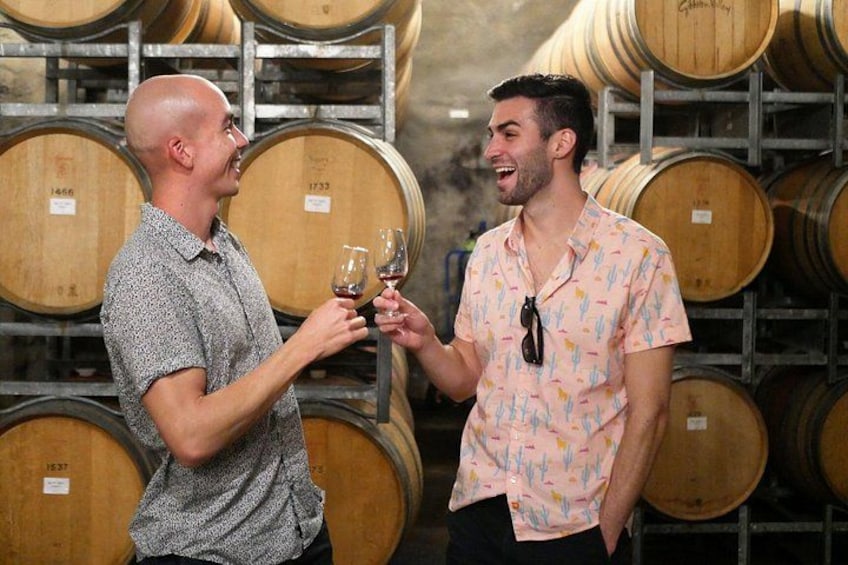 Due persone brindano con bicchieri di vino in una cantina con botti di legno. 5