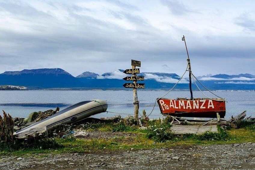 Een boot genaamd 'Palmanza' aan een steiger, een richtingwijzer en een bergachtig landschap op de achtergrond. 1