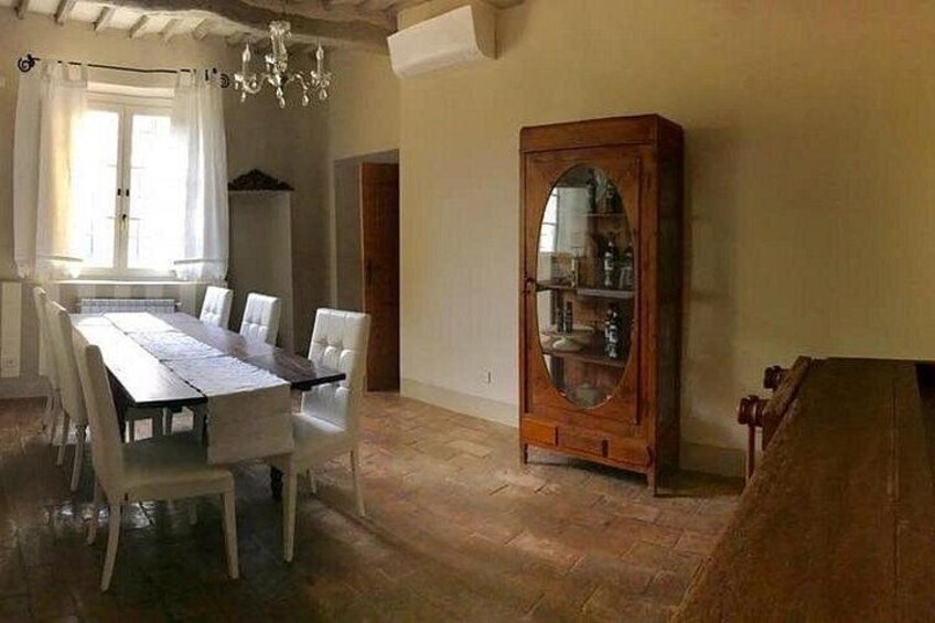 Un comedor con una mesa y sillas de madera, un aparador grande de madera y una araña. 2