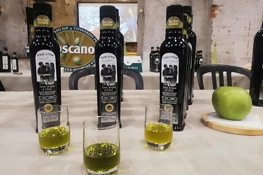 Botellas de aceite de oliva Toscano y vasos con aceite de oliva sobre una mesa. 4