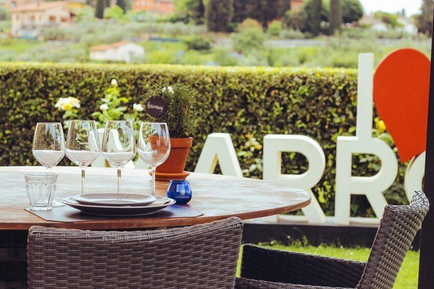 A table set with wine glasses and plates, a potted plant, and a sign with the word 'ARRO'. 5