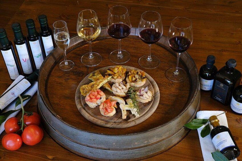 A wooden tray with seafood appetizers, wine glasses, and bottles of wine on a table. 4