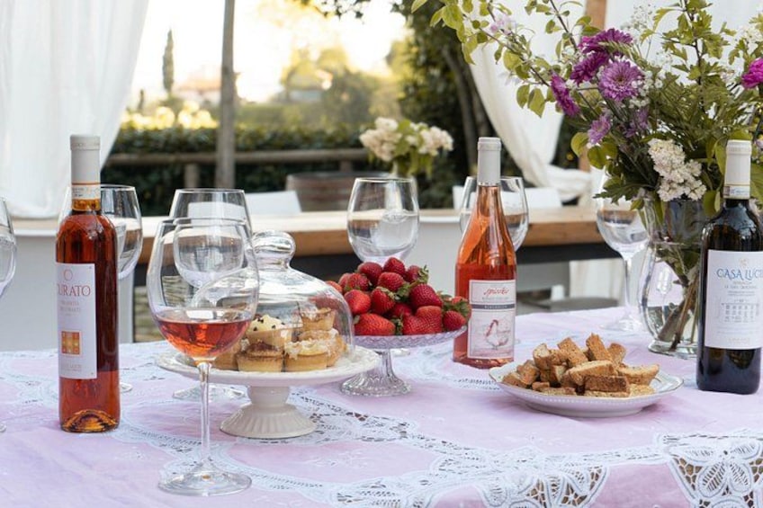 A table set outdoors with wine bottles, glasses, strawberries, and pastries. 3