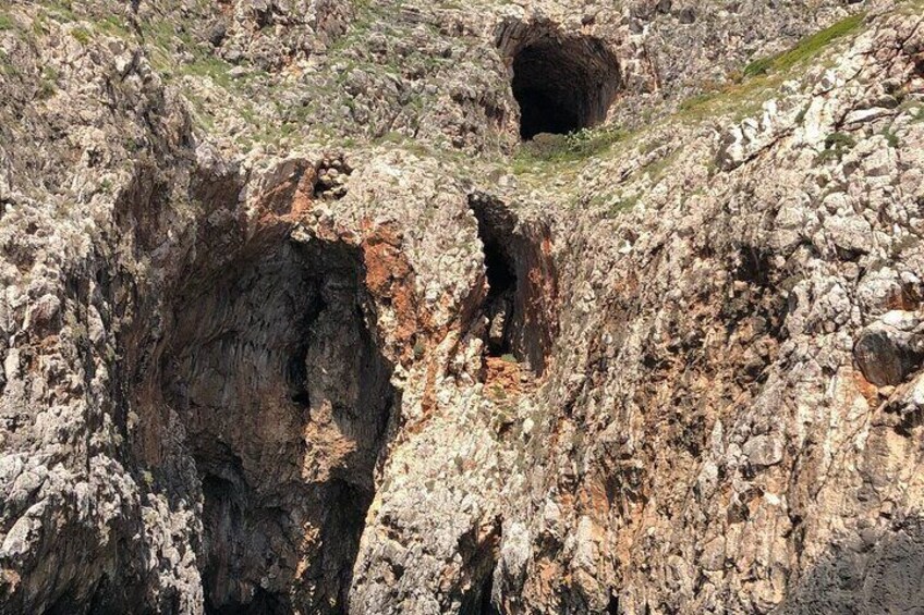 A rocky terrain with a large cave opening and a smaller cave nearby. 5