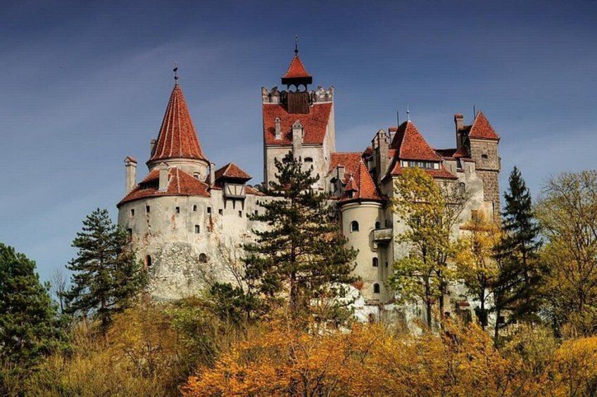 A historic castle with multiple towers and turrets, surrounded by autumn foliage. 5