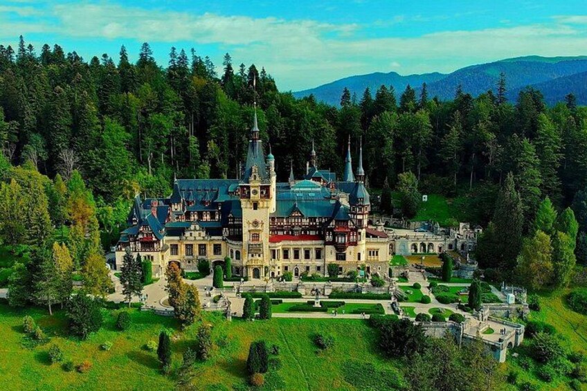 A large, historic building surrounded by lush greenery and mountains. 4