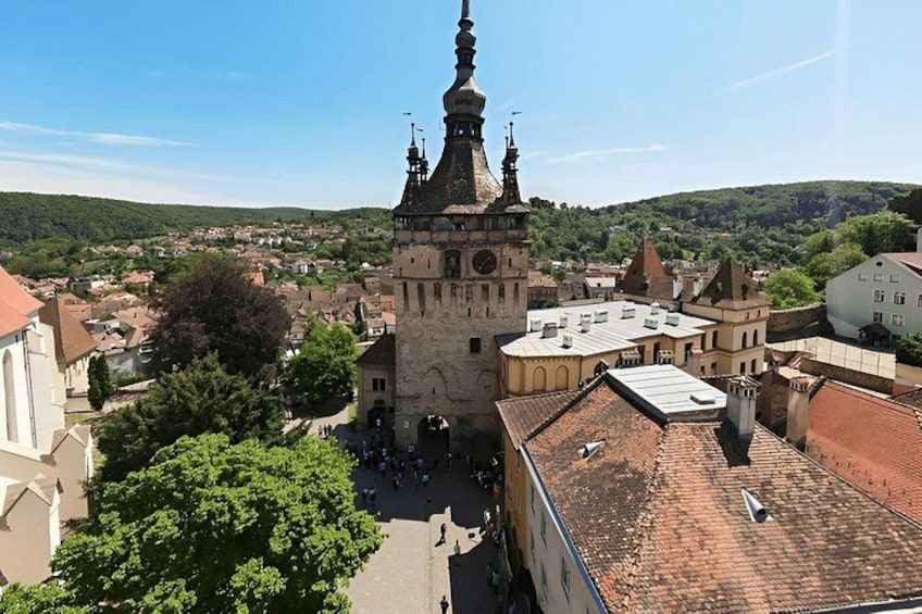A historic church with a tall spire, surrounded by buildings and a hilly landscape. 1
