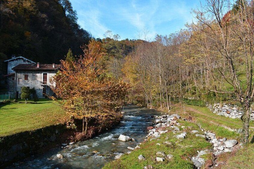 A river flowing through a valley with a house on the left and trees on both sides. 3