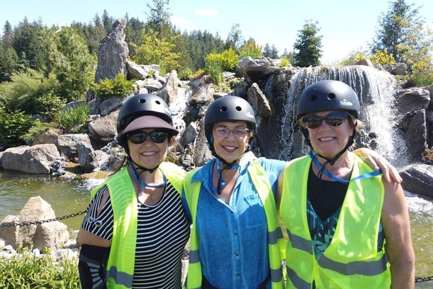 Three people wearing helmets and safety vests standing in front of a waterfall. 4