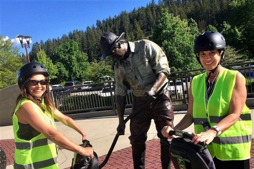 Two people in safety vests and helmets interacting with a statue. 5