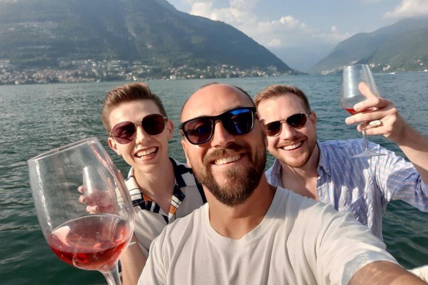 Drie personen maken een selfie, met een meer en bergen op de achtergrond. 3