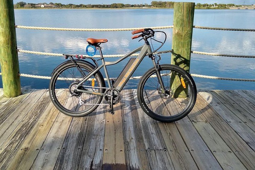 Una bicicleta estacionada en un muelle de madera junto al agua. 1