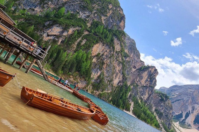 A wooden boat docked at a pier with a mountainous backdrop. 1