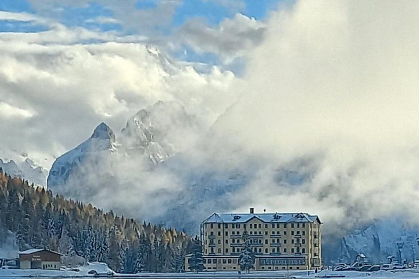 A snow-covered mountain, a building, and a forest. 2