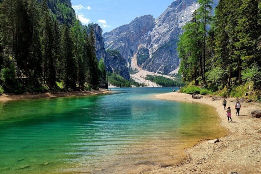 A clear lake surrounded by mountains, a sandy beach, and dense forest. 5