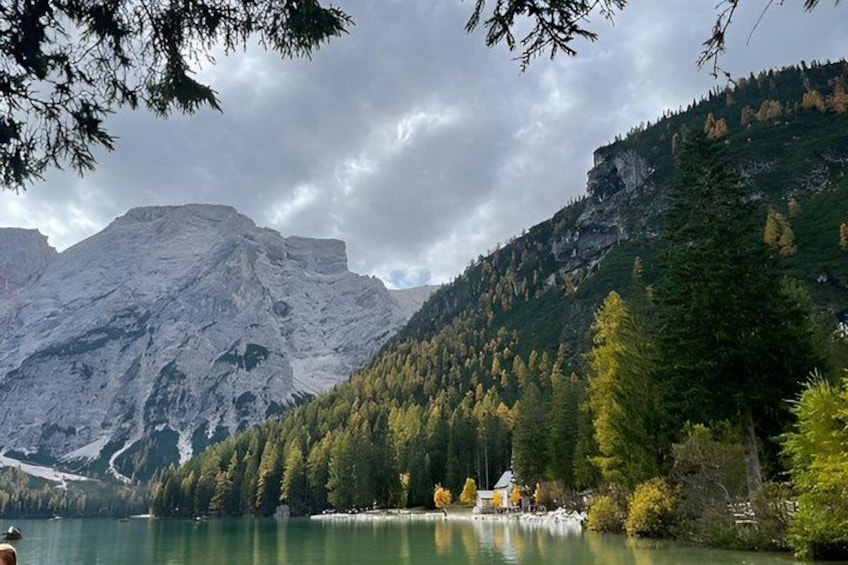 A mountain lake with a cabin, dense forest, and a rocky mountain. 4