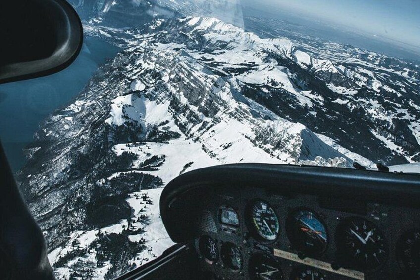 A mountainous landscape with snow-covered peaks and a cockpit view of an aircraft. 1