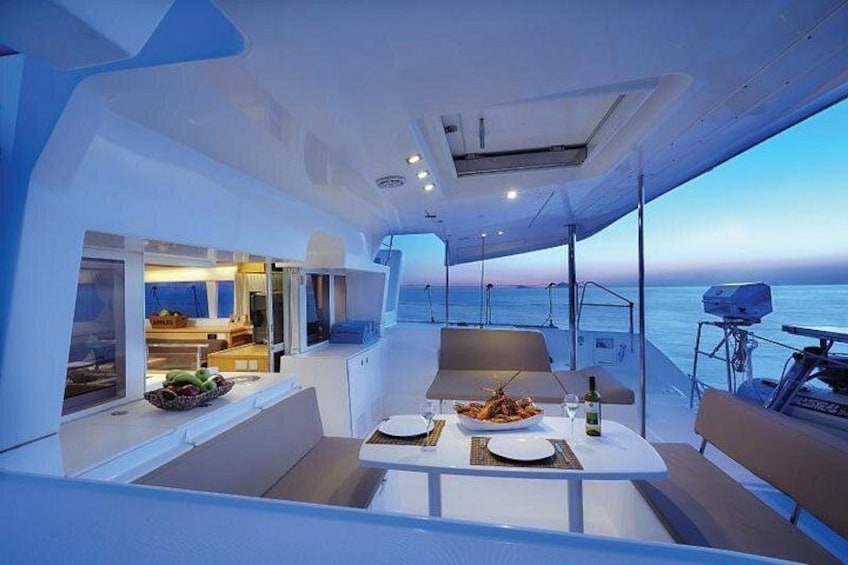 A modern boat interior with a dining area, a kitchen, and a view of the sea. 2